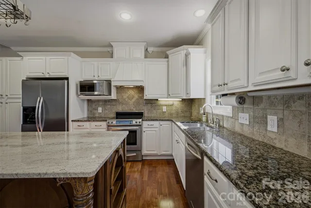 a kitchen with kitchen island granite countertop a sink counter top space appliances and cabinets