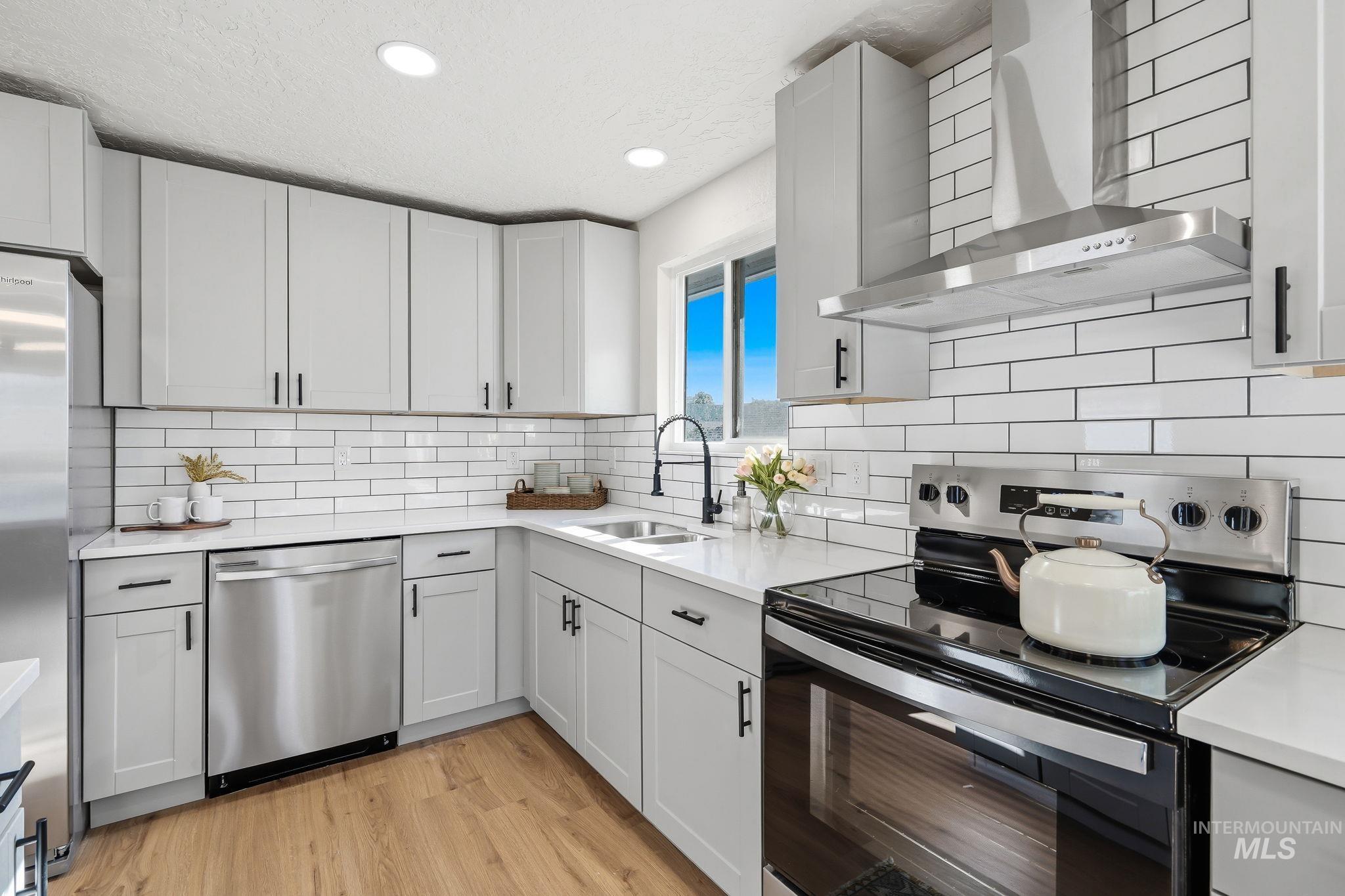 1990 Panama Street Boise, ID 83705 - Photo 25 of 50 Modern kitchen featuring light gray cabinetry, stainless steel appliances, a white subway tile backsplash, recessed lighting, and wood-finish flooring