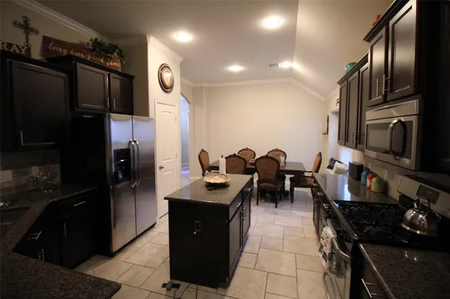 a kitchen with granite countertop a refrigerator stove and sink