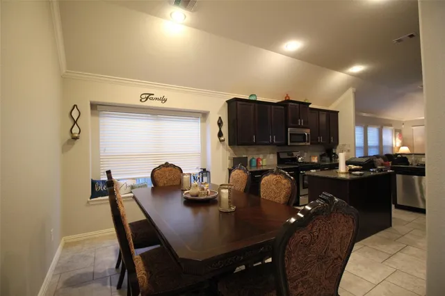 a kitchen with a dining table chairs and a refrigerator