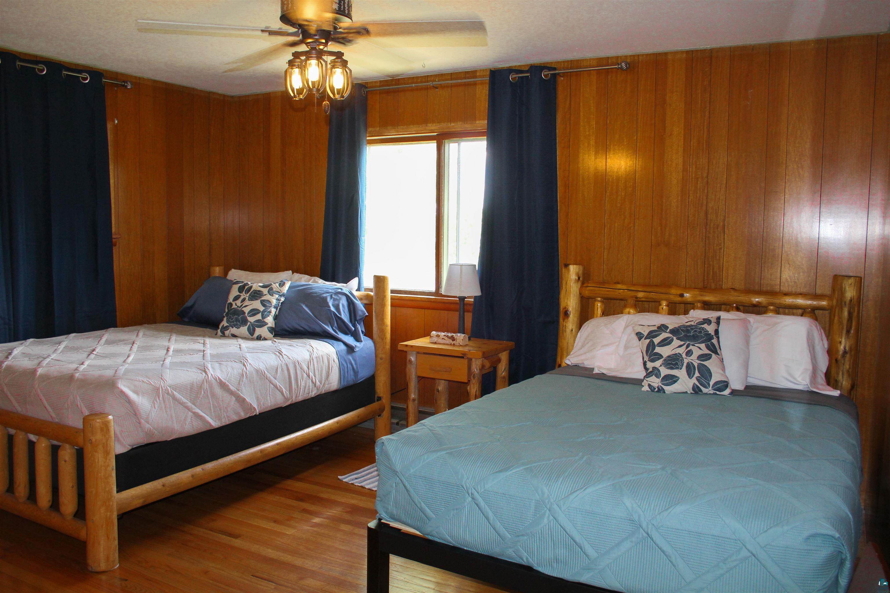 444 Fernberg Road, Unit 11 Ely, MN 55731 - Photo 3 of 19 Bedroom with wood walls, a ceiling fan, and wood finished floors