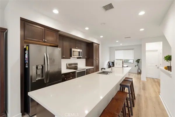 a large kitchen with kitchen island a refrigerator a stove a sink a dining table and chairs