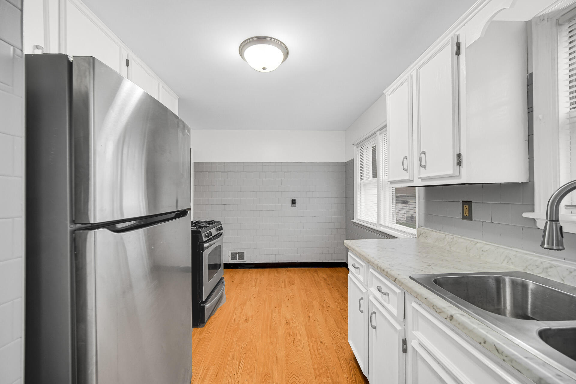 4641 Delaware Street Gary, IN 46409 - Photo 14 of 22 a kitchen with stainless steel appliances a refrigerator a sink a stove and white cabinets