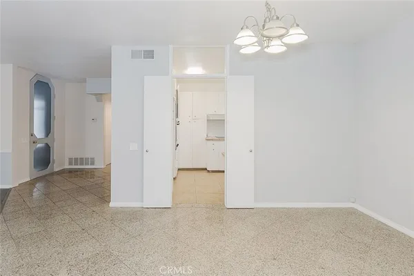 a view of an empty room with a chandelier fan
