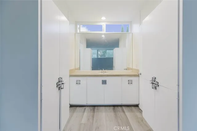 a view of bathroom with a sink mirror and window