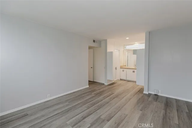 a view of a room with wooden floor and a kitchen
