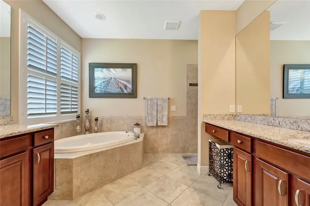 a bathroom with a granite countertop sink a mirror a bathtub and next to a window