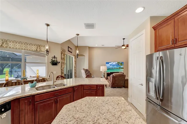 a kitchen with stainless steel appliances kitchen island granite countertop a refrigerator and a sink