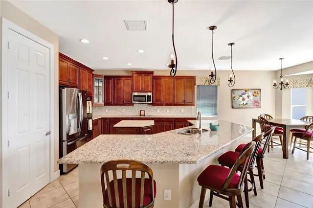 a open kitchen with stainless steel appliances granite countertop a stove a refrigerator a kitchen island a dining table and chairs with wooden floor
