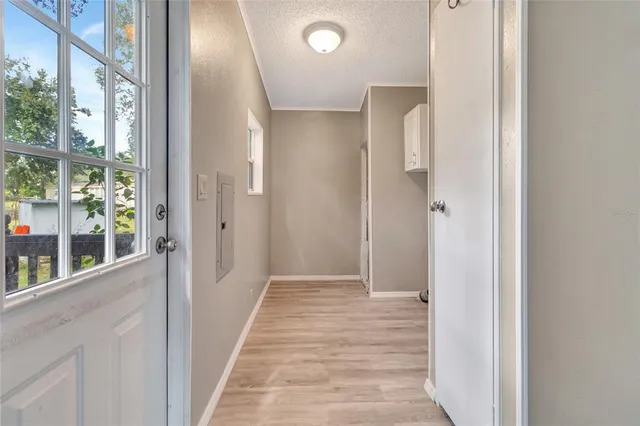 a view of a hallway with wooden floor and a bathroom