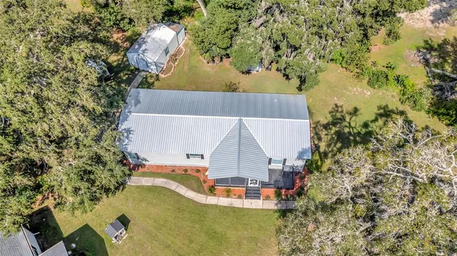 an aerial view of a house with swimming pool and large trees