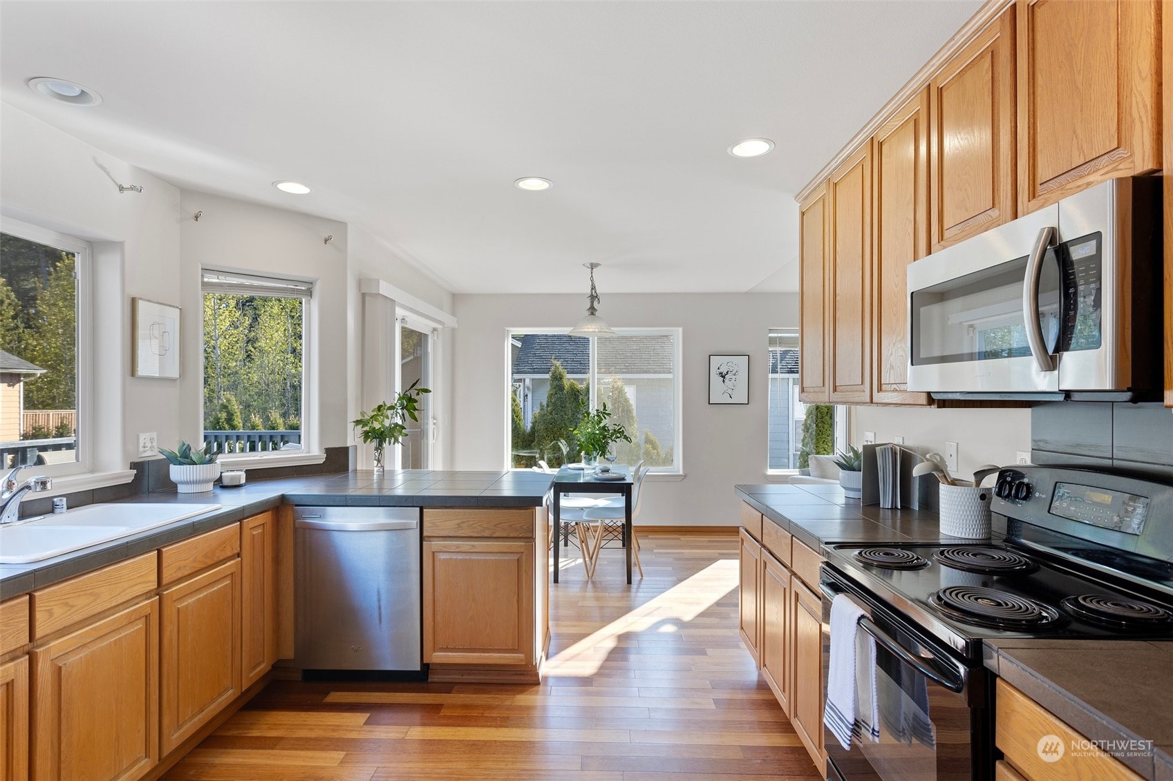 15317 Sunset Road Bothell, WA 98012 - Photo 7 of 24 a kitchen with stainless steel appliances granite countertop a stove a sink dishwasher and white cabinets with wooden floor
