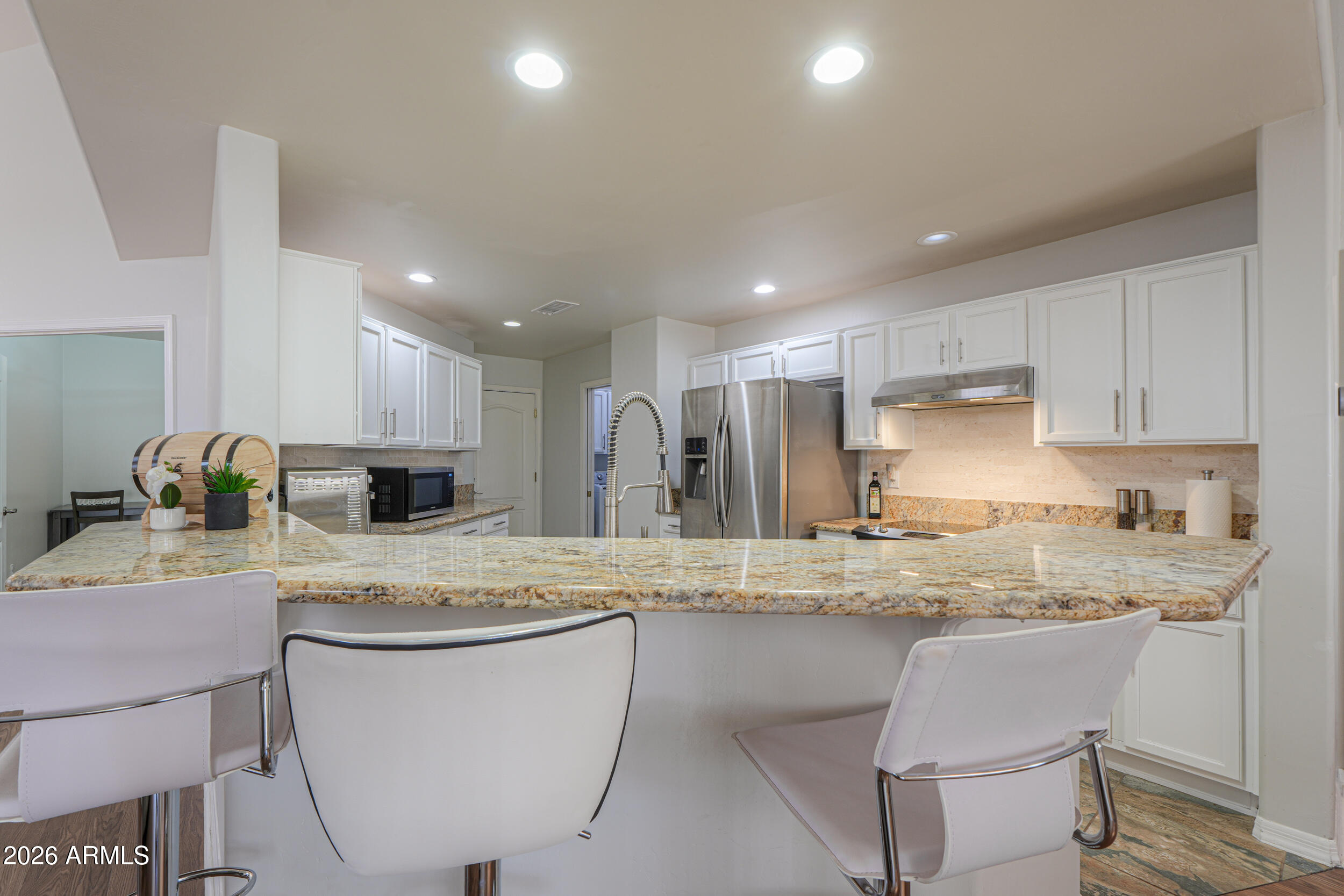 5830 East McKellips Road, Unit 27 Mesa, AZ 85215 - Photo 14 of 47 a kitchen with kitchen island granite countertop a table chairs sink and cabinets