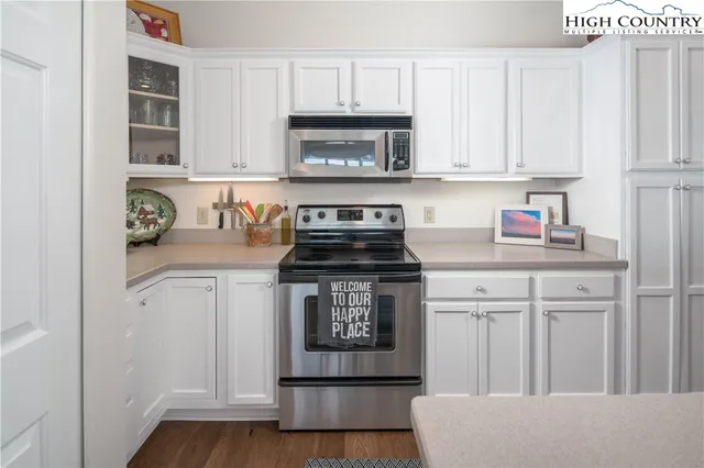 a kitchen with white cabinets and a stove with wooden floor