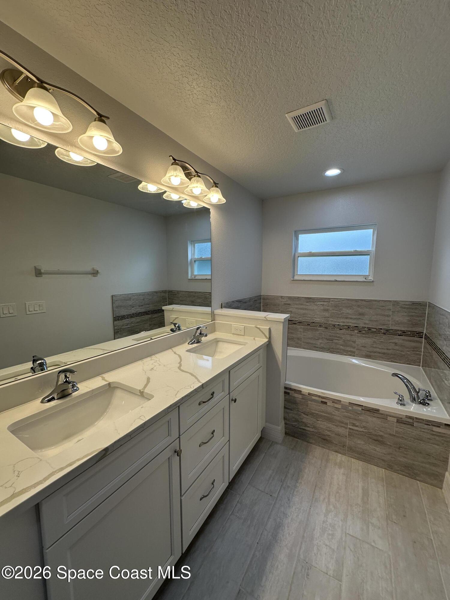 650 Rockinghorse Road Melbourne, FL 32935 - Photo 14 of 16 a spacious bathroom with a bathtub sink and mirror
