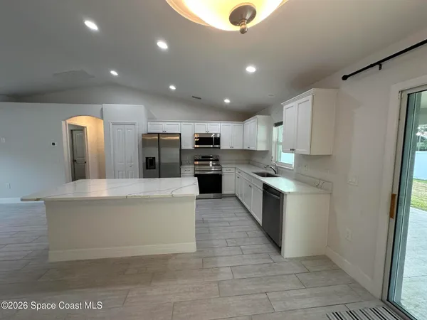 a large kitchen with stainless steel appliances kitchen island a large counter top and a stove top oven