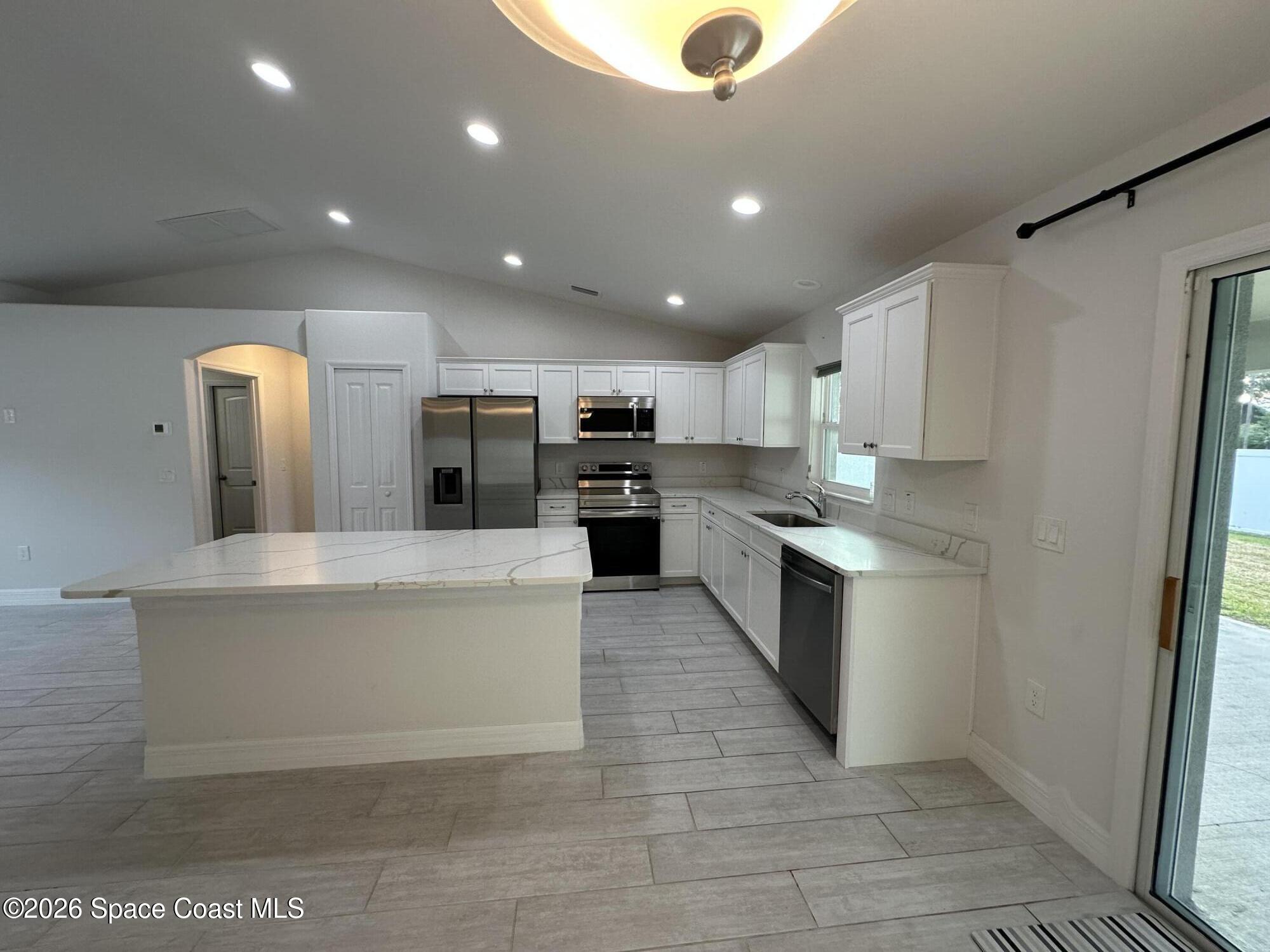 650 Rockinghorse Road Melbourne, FL 32935 - Photo 5 of 16 a large kitchen with stainless steel appliances kitchen island a large counter top and a stove top oven