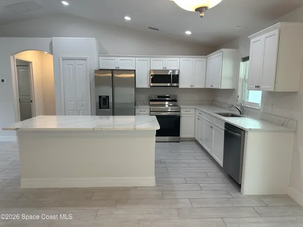 a large kitchen with stainless steel appliances granite countertop a stove a sink dishwasher a refrigerator and a oven