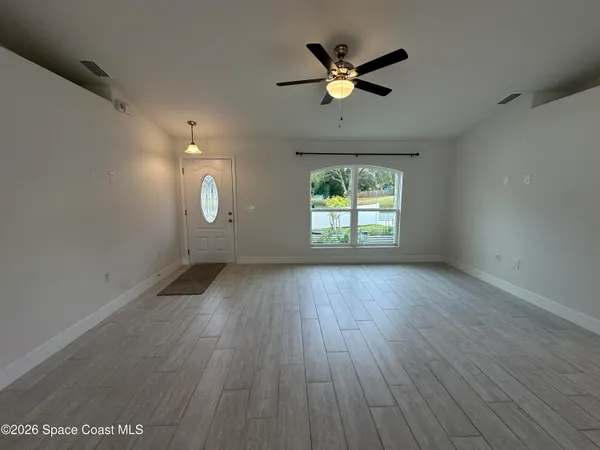 an empty room with wooden floor and windows