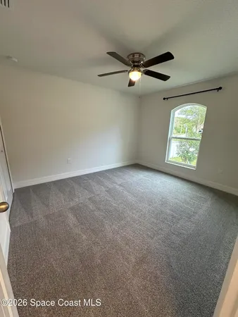 an empty room with windows and fan