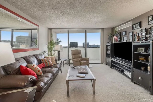 a living room with furniture a flat screen tv and a floor to ceiling window