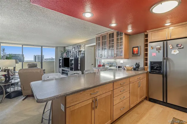 a kitchen with stainless steel appliances granite countertop a refrigerator a sink dishwasher a dining table and chairs with wooden floor