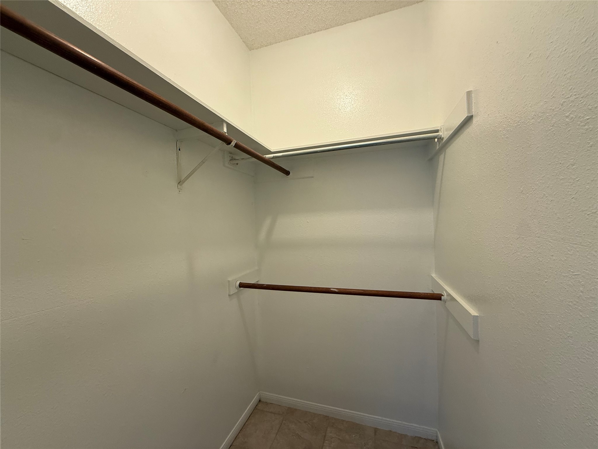 203 East 31st Street, Unit 101 Austin, TX 78705 - Photo 13 of 24 Walk-in closet featuring multiple hanging rods, overhead shelving, and tile flooring