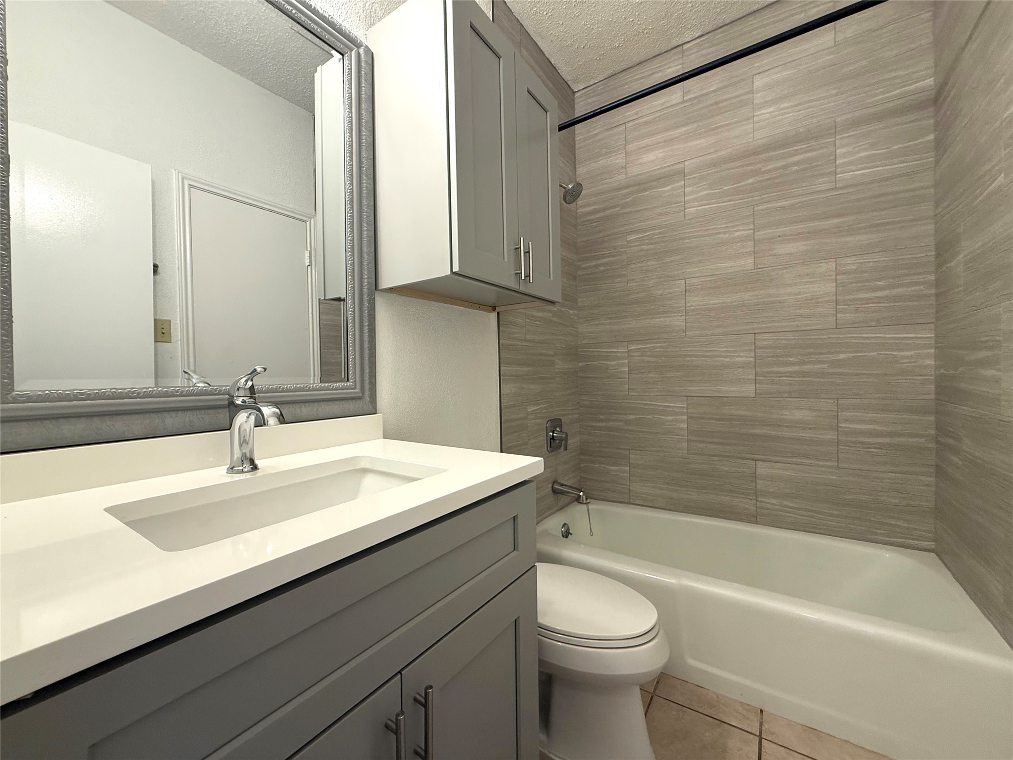 203 East 31st Street, Unit 101 Austin, TX 78705 - Photo 14 of 24 Bathroom featuring a white integrated sink with a chrome faucet, gray vanity, framed mirror, and built-in gray cabinetry