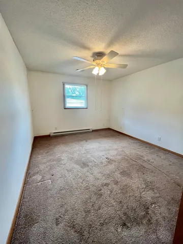 an empty room with windows and fan