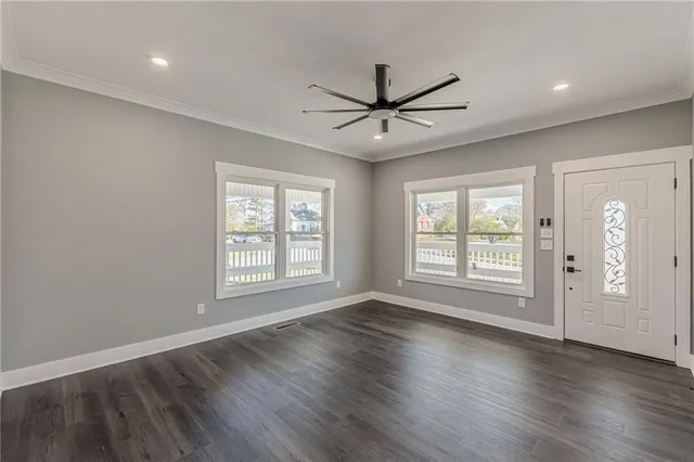 a view of an empty room with wooden floor and a window