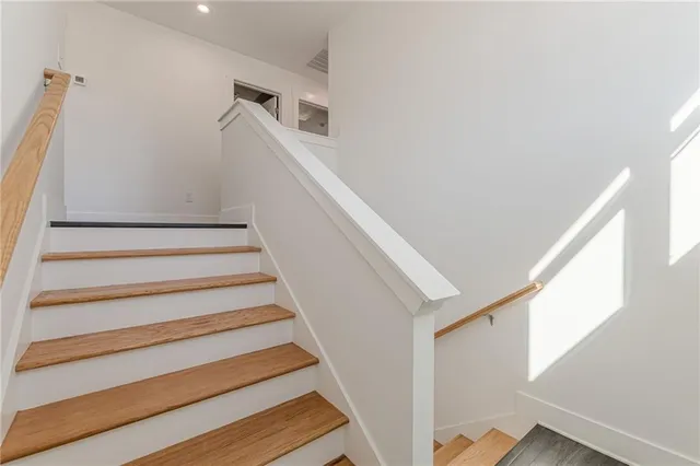 a view of an empty room with wooden floor and stairs