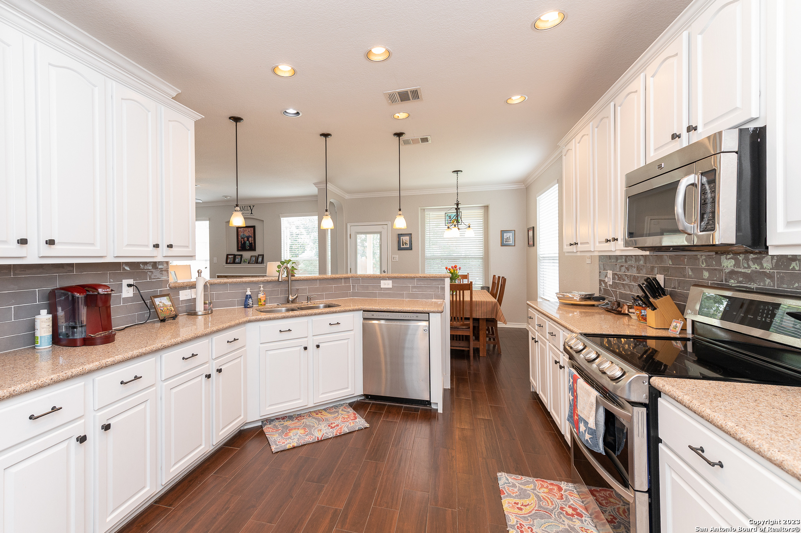 2604 Patron Village Schertz, TX 78108 - Photo 19 of 52 a large kitchen with stainless steel appliances granite countertop a stove a sink dishwasher and a microwave oven with wooden floor