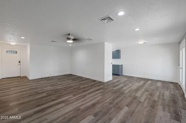 a view of an empty room with wooden floor and a ceiling fan