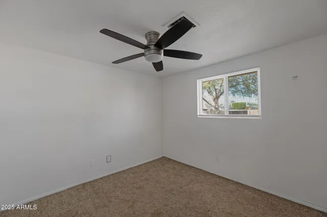 an empty room with a window and a fan