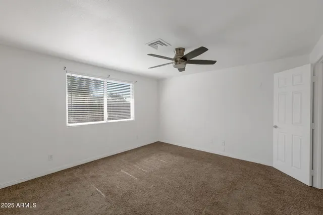 a view of a big room with a ceiling fan and a window