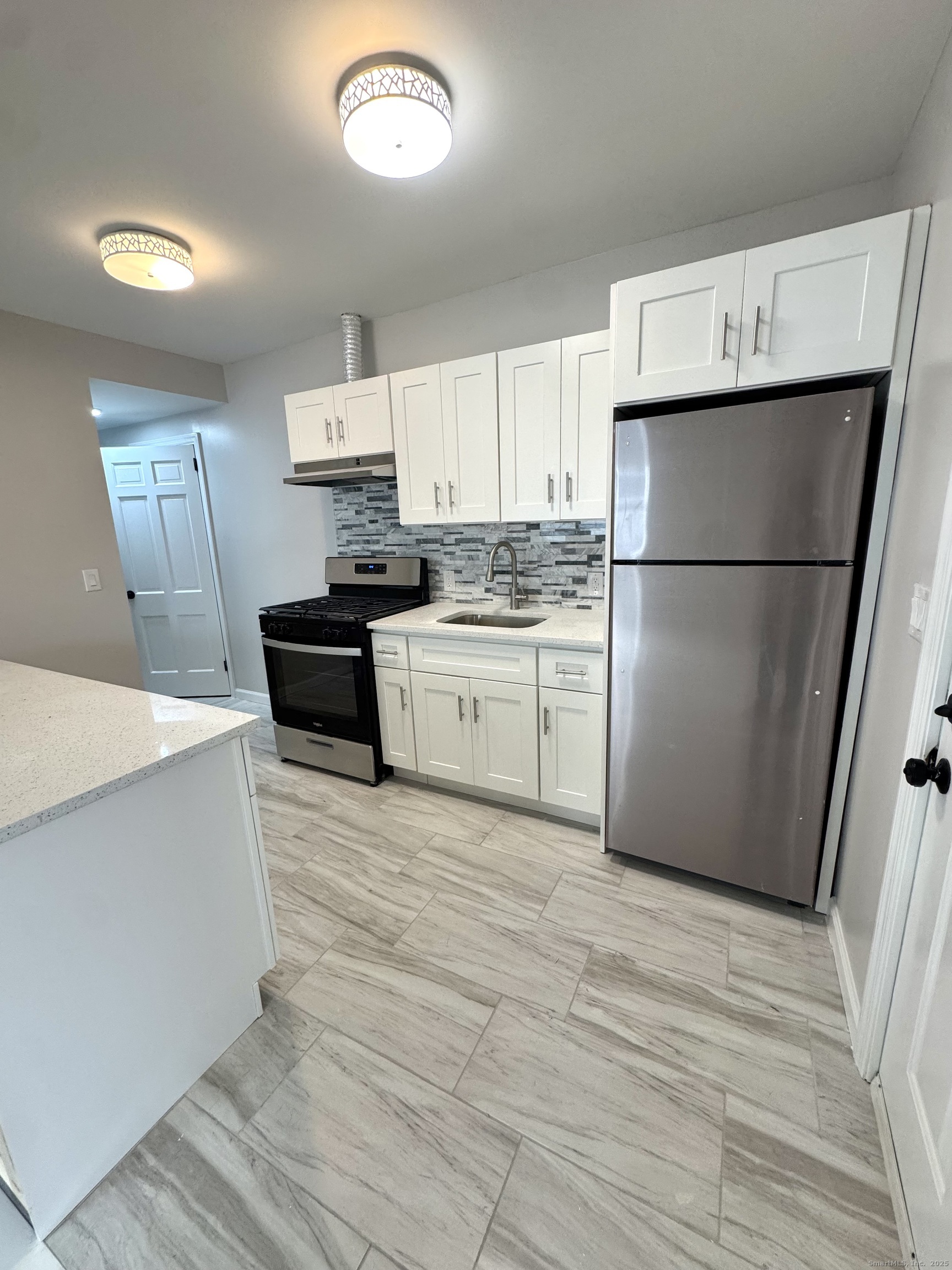 24 Woodbury Avenue, Unit 1A Norwalk, CT 06850 - Photo 2 of 7 a kitchen with a refrigerator a stove top oven a sink and dishwasher