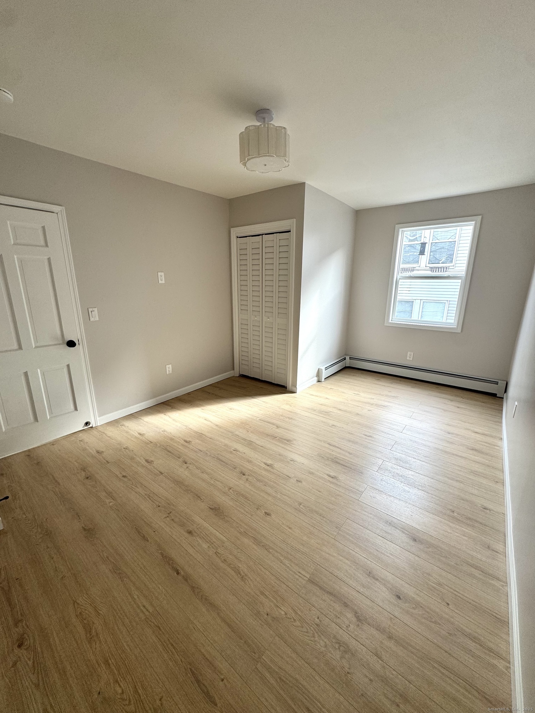 24 Woodbury Avenue, Unit 1A Norwalk, CT 06850 - Photo 4 of 7 a view of an empty room with wooden floor and a window