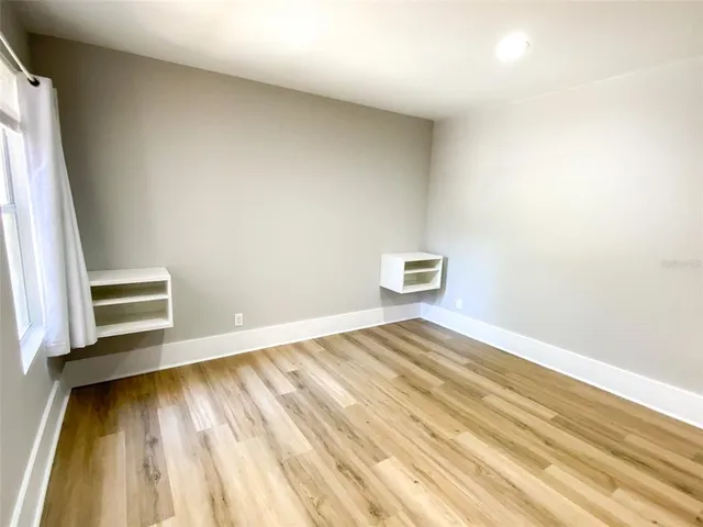 a view of empty room with wooden floor and fan