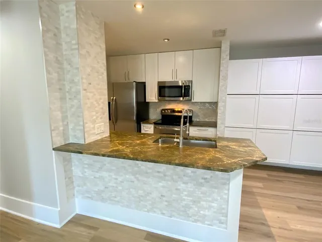 a kitchen with stainless steel appliances granite countertop a sink a stove and a granite counter top