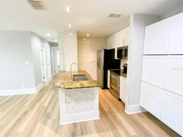 a kitchen with stainless steel appliances kitchen island granite countertop a refrigerator and a sink