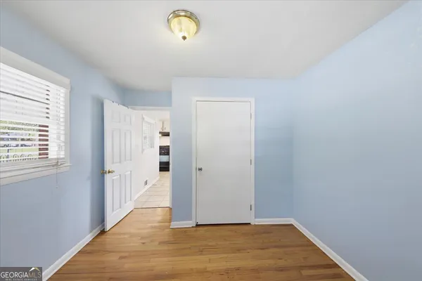 a view of an empty room with wooden floor and a window