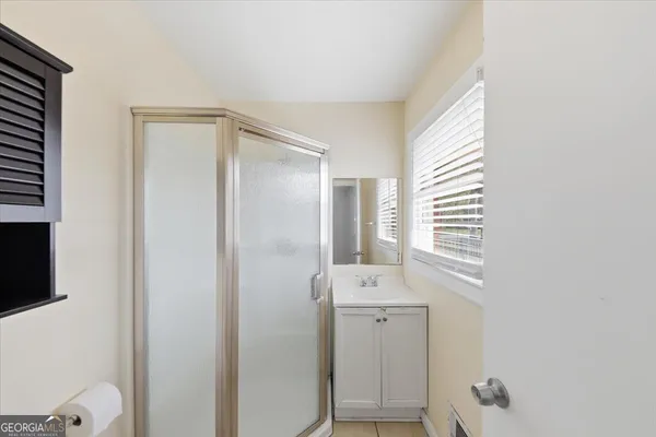 a bathroom with a shower a sink and a window
