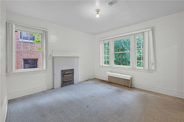 an empty room with windows and fireplace