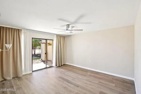 an empty room with wooden floor and a ceiling fan