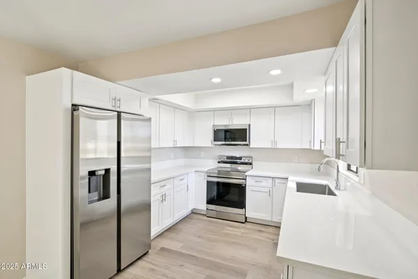 a kitchen with stainless steel appliances granite countertop a refrigerator a stove and a sink with wooden floor
