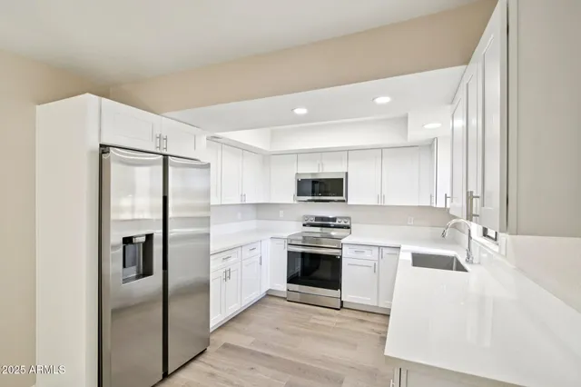 a kitchen with stainless steel appliances granite countertop a refrigerator a stove and a sink with wooden floor