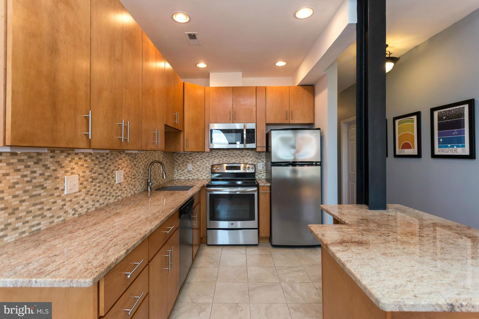 1918 18th Street Northwest, Unit 41 Washington, DC 20009 - Photo 7 of 30 a kitchen with stainless steel appliances granite countertop a sink a stove and a refrigerator