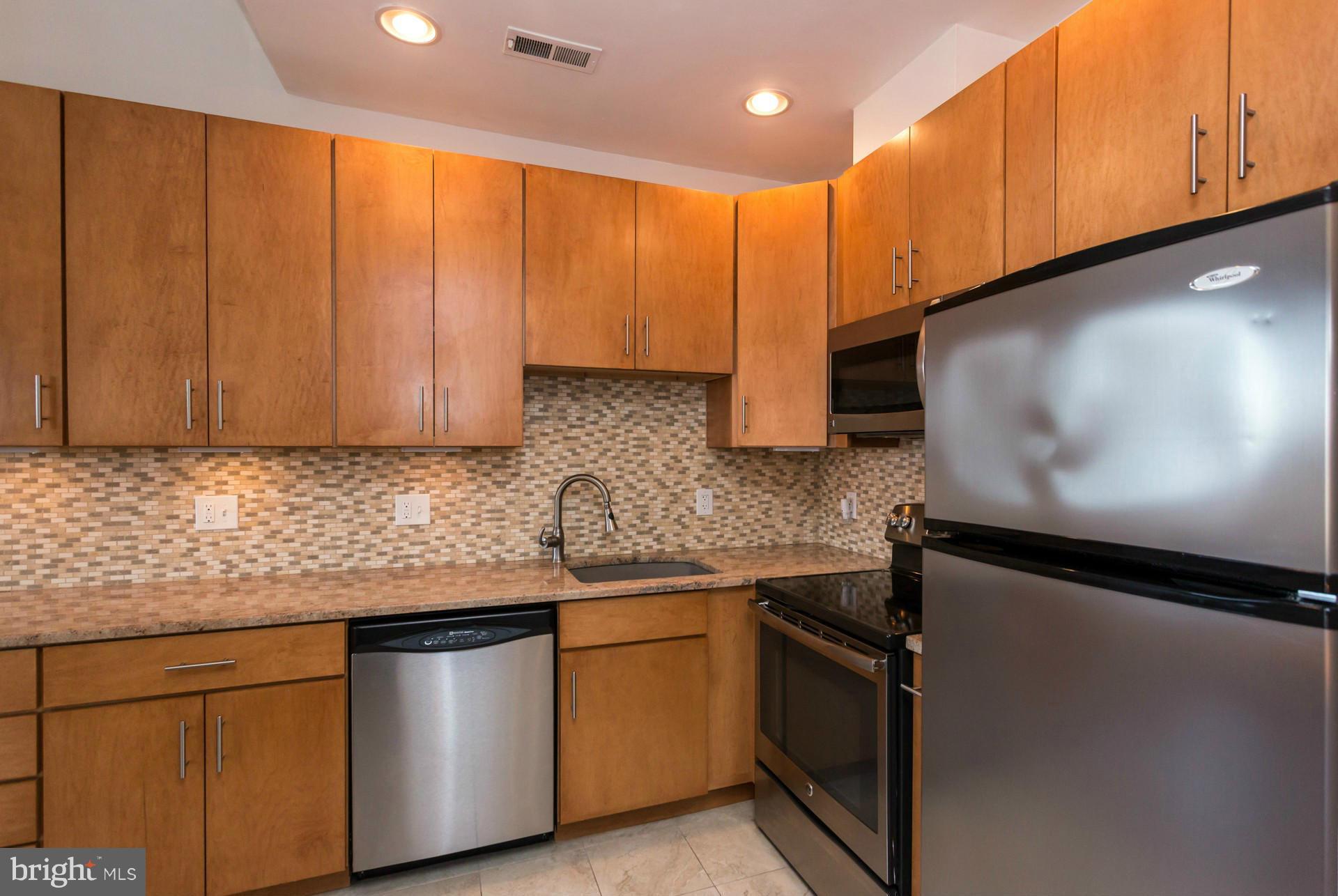 1918 18th Street Northwest, Unit 41 Washington, DC 20009 - Photo 8 of 30 a kitchen with stainless steel appliances granite countertop wooden cabinets a stove a sink and a microwave