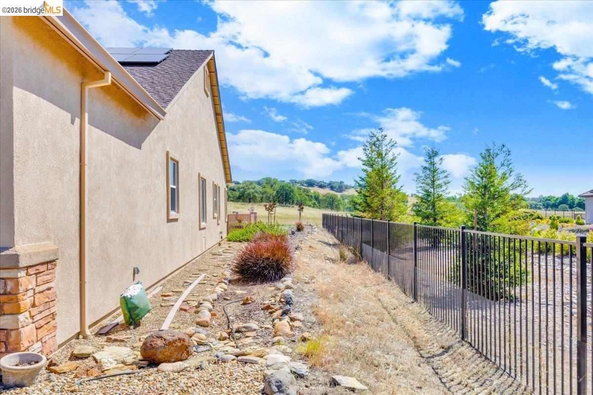 158 Rock Ridge Lane Copperopolis, CA 95228 - Photo 58 of 72 Stucco exterior featuring multiple windows and a low-sloped roof with solar panels