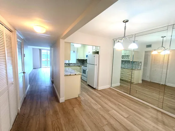 a view of a kitchen with wooden floor and a refrigerator